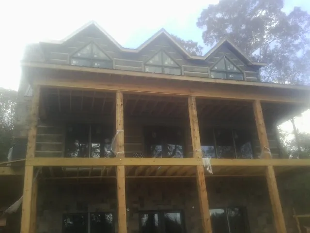 Dormers and porch framing on a large log home under construction — Roof Coating work by our crew in Lake Park