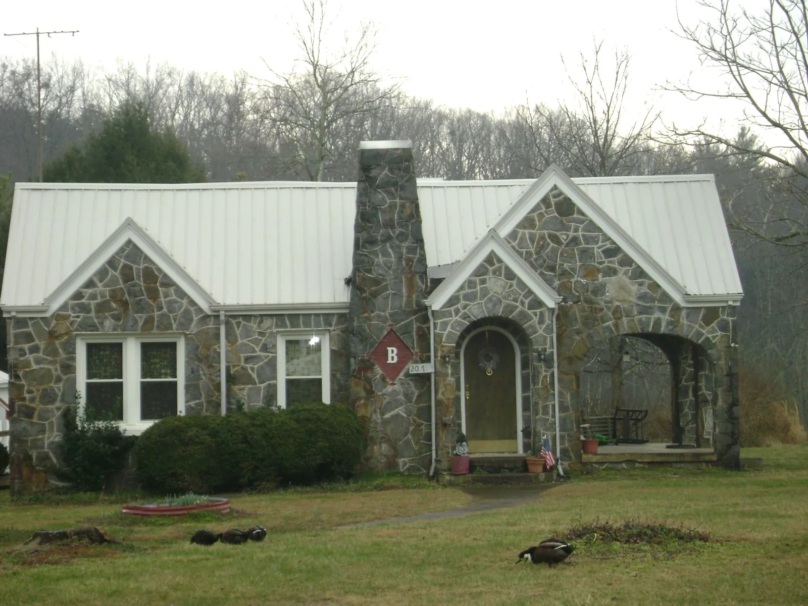 White metal roof on a stone cottage with steep gables in Lake Park