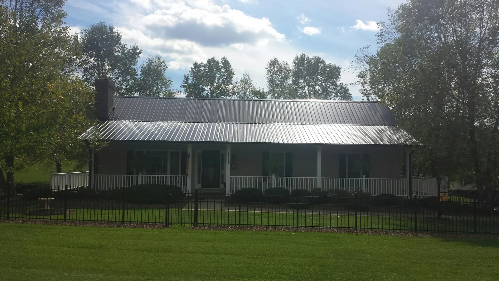 Gray metal roof on a brick ranch with a full width front porch — Gutter Guard Installation work by our crew in Lake Park
